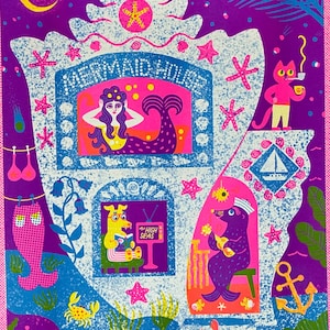 May include: A rectangular art print featuring a purple background with a large white seashell structure labeled MERMAID HOUSE. The illustration depicts a mermaid, a dog reading a book titled THE HIGH SEAS, a seal playing a guitar, and a cat.