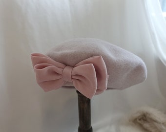 Elegante boina de lana rosa pálido con lazo rosa dulce: accesorio acogedor de moda de invierno
