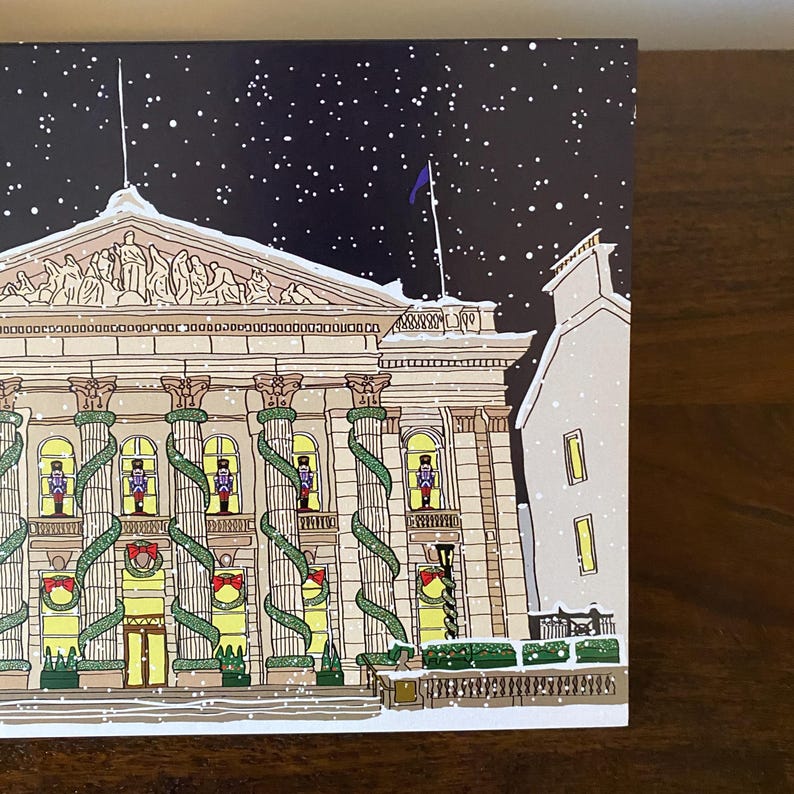 May include: A snowy night scene with a large building decorated with evergreen garlands and nutcracker figures in the windows. The building has a classical architectural style with columns and a decorative cornice.