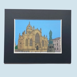 May include: A framed print of a detailed illustration of a church building with a statue in front of it. The church is a light brown color with a tall steeple and many windows. The statue is a dark green color and is standing on a pedestal. The print is set against a blue sky background.