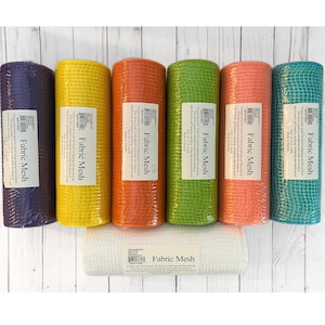 May include: A collection of colorful fabric mesh rolls in various shades, including purple, yellow, orange, green, coral, and teal. A white roll of fabric mesh is also present. Each roll has a label that reads "Fabric Mesh".