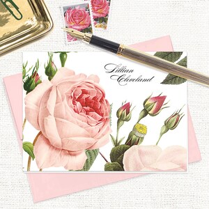 May include: A white card with a pink rose and green leaves. The text "Lillian Cleveland" is printed in black cursive script.