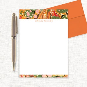 May include: White stationery with a colorful marbled border and the name "Kinsley Phillips" printed in orange at the top.