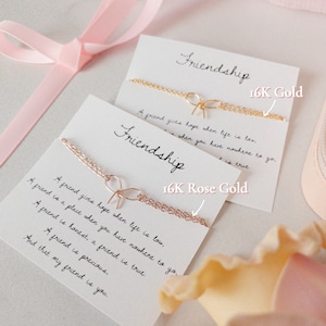 May include: Two cards with the word "Friendship" written on them. The cards are decorated with gold and rose gold chains and the text "16K Gold" and "16K Rose Gold". The cards are surrounded by pink and white flowers.