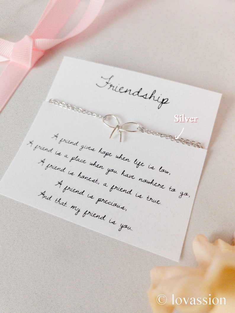 May include: A silver friendship bracelet with a bow charm and a card with the text "Friendship" and a poem about the importance of friendship.