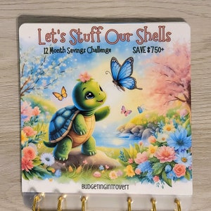 May include: A colorful illustration of a turtle with a flower on its head standing on a rock in a field of flowers. A blue butterfly is flying above the turtle. The text "Let's Stuff Our Shells 12 Month Savings Challenge SAVE $750+" is at the top of the image. The text "BUDGETINGINTROVERT" is at the bottom of the image.
