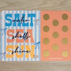 May include: A rectangular card with a blue and white striped background on the left and a peach background with gold circles on the right. The card features the words "SALT water SEA shells SUN shine" in blue, peach, and yellow.
