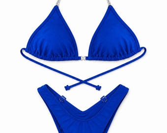 Könnte beinhalten: Ein leuchtend königsblaues Bikini-Set bestehend aus einem Triangel-Oberteil mit silbernen Kettenträgern und einem Mittelstück. Das passende hoch geschnittene Bikini-Unterteil hat einen V-förmigen Bund mit kleinen silbernen Metallakzenten an den Seiten.