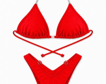 Könnte beinhalten: Ein leuchtend roter zweiteiliger Bikini mit Triangel-Oberteil, silbernen Ketten-Trägern und einem kleinen Verbindungsstück in der Mitte. Das passende hoch geschnittene Bikini-Unterteil hat dünne Seitenbänder und silberne Ring-Details.
