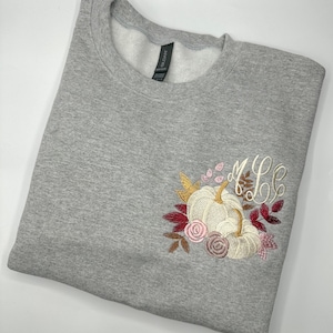May include: Gray sweatshirt with embroidered pumpkins, fall leaves, and the monogram "M.L.C."