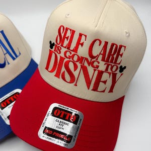 May include: A baseball cap with a red bill and a beige crown. The cap features the embroidered phrase "SELF CARE IS GOING TO DISNEY" in red, with Mickey Mouse silhouettes. The cap has a red button on top and a "OTTO" sticker.