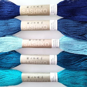 May include: Five skeins of Sashiko embroidery thread in shades of blue, from deep navy to turquoise. Each skein is labeled with Japanese text and the brand name "Sashiko". The thread is 100% cotton and made in Japan.