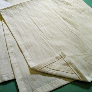 May include: Three white cotton dish towels folded together. The towels have a textured, ribbed surface.