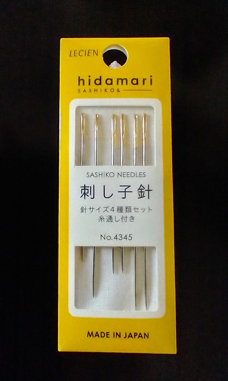 Op de afbeelding: Een geel pakketje Lecien Hidamari Sashiko-naalden. Het pakketje heeft de tekst "Sashiko Needles" en "刺し子針" in het Japans. Het pakketje heeft ook de tekst "No. 4345" en "Made in Japan".