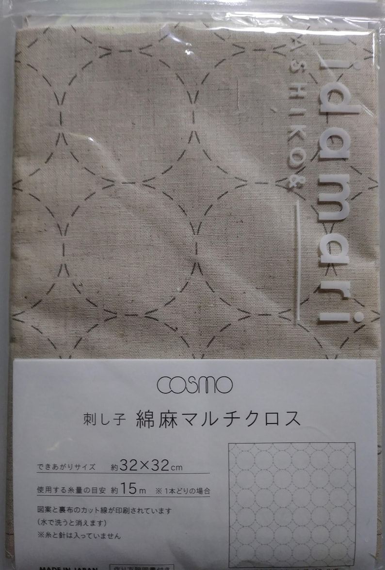 K&ouml;nnte beinhalten: Verpackter beigefarbener Stoff mit einem gestickten Punktmuster. Die Verpackung enth&auml;lt ein Etikett mit japanischem Text und dem Markennamen "cosmo". Der Stoff misst ca. 32 x 32 cm.