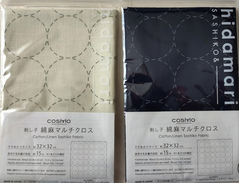 K&ouml;nnte beinhalten: Zwei verpackte Baumwoll-/Leinen-Sashiko-Stoffe. Einer ist cremefarben mit grau gen&auml;hten Kreisen, der andere marineblau mit wei&szlig; gen&auml;hten Kreisen. Jede Packung hat Text in Japanisch und Englisch, einschlie&szlig;lich der Marke "cosmo".