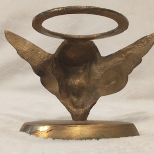 May include: Gold metal angel figurine with wings and a halo. The angel is standing on a round base.