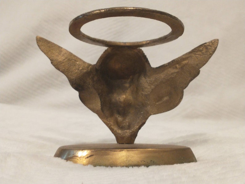 May include: Gold metal angel figurine with wings and a halo. The angel is standing on a round base.