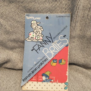 May include: A package of two iron-on jean patches featuring a whimsical design of children playing with blocks. The package is labeled "Fanny Brite's" and "Topsy Turvey #602".