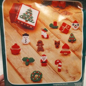 May include: A plastic canvas kit for making 14 miniature Christmas ornaments. The kit includes a keepsake box, yarn, needles, and instructions. The ornaments include a Christmas tree, snowman, gingerbread man, Santa Claus, and a candy cane.