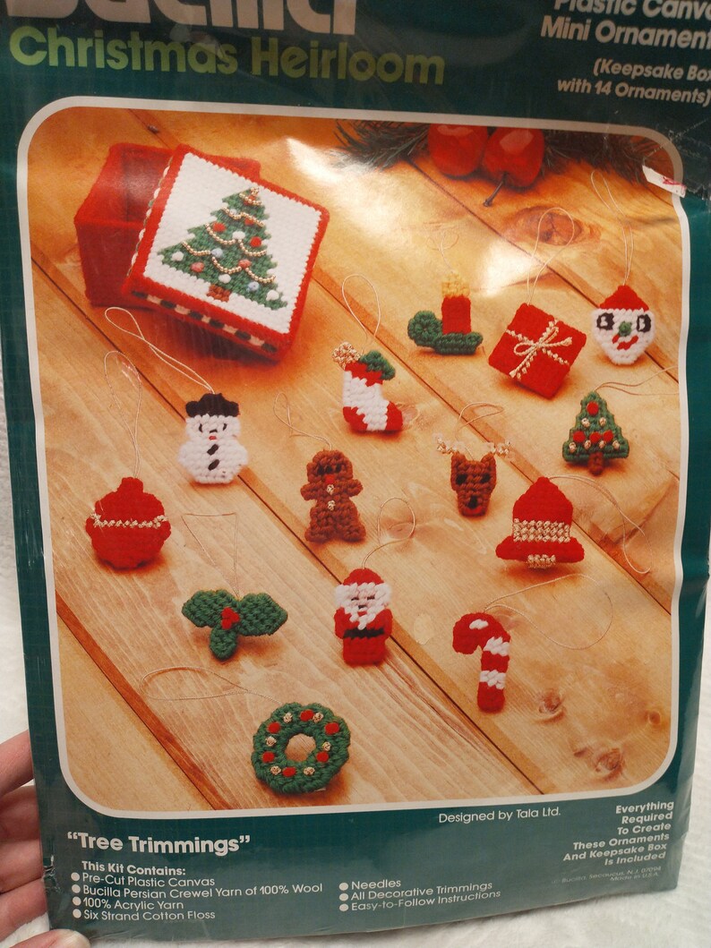 May include: A plastic canvas kit for making 14 miniature Christmas ornaments. The kit includes a keepsake box, yarn, needles, and instructions. The ornaments include a Christmas tree, snowman, gingerbread man, Santa Claus, and a candy cane.