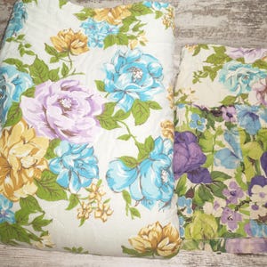 May include: Two floral patterned pillowcases with a white background and a variety of colors including yellow, blue, purple, and green.