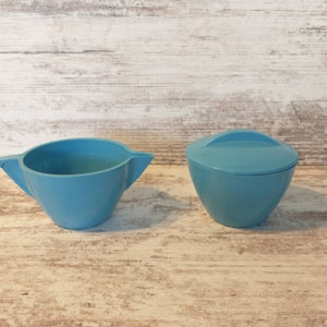 May include: A blue ceramic creamer and sugar bowl set. The creamer has a spout and a handle. The sugar bowl has a lid.