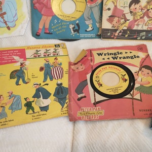 May include: A collection of vintage children's records with colourful covers featuring illustrations of nursery rhymes and a cartoon character. The records are labelled "Peter Pan Records" and "More Playing Time Records".