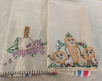 May include: Two vintage embroidered tea towels. One features a bunch of grapes and a bottle of wine. The other features three embroidered vegetables with faces: a carrot, an orange, and a potato.