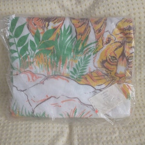 Op de afbeelding: Een witte strandhanddoek met een print van een tijger en junglebegroeiing. De handdoek is verpakt in plastic en heeft een label met de tekst "TIGER  DOUBLE  SIZE  72 x 36"