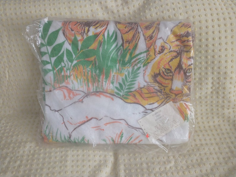 Op de afbeelding: Een witte strandhanddoek met een print van een tijger en junglebegroeiing. De handdoek is verpakt in plastic en heeft een label met de tekst "TIGER  DOUBLE  SIZE  72 x 36"