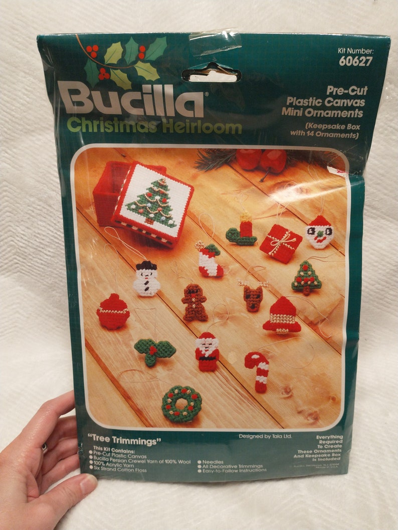 May include: A Bucilla Christmas Heirloom craft kit with 14 pre-cut plastic canvas mini ornaments. The kit includes everything needed to create the ornaments, including yarn, needles, and a keepsake box. The ornaments feature a variety of Christmas themes, such as a snowman, a gingerbread man, and a Santa Claus.