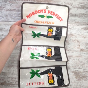 May include: White fabric organizer with three clear pockets. The pockets are labeled "MISC", "BILLS", and "LETTERS". Each pocket has a black tree branch with a green leaf and an orange and black owl.