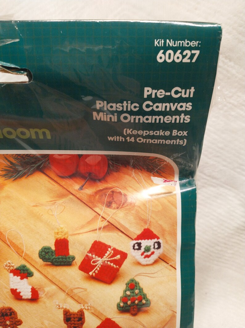 May include: A plastic canvas craft kit with 14 pre-cut mini ornaments for Christmas. The ornaments include a snowman, a Christmas tree, a stocking, a gift, a candle, and a reindeer. The kit comes with a keepsake box. Kit number 60627.