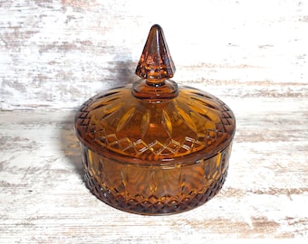 May include: A vintage amber glass candy dish with a diamond pattern and a pointed lid.