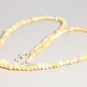 May include: A delicate necklace made of small, iridescent opal beads. The necklace is strung on a silver chain and has a silver clasp.