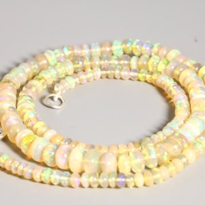 May include: A multi-strand necklace made of iridescent white opal beads. The necklace is made of small, round beads and has a silver clasp.