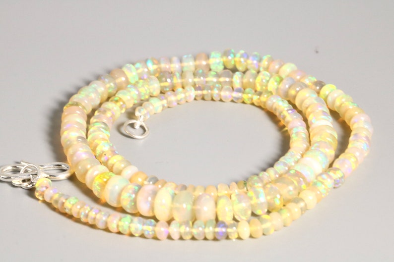 May include: A multi-strand necklace made of iridescent white opal beads. The necklace is made of small, round beads and has a silver clasp.