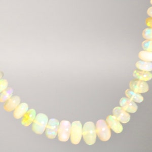 May include: A strand of white opal beads with iridescent shimmer. The beads are round and smooth, and the necklace is approximately 18 inches long.