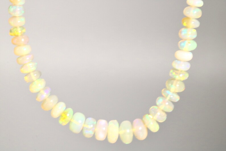 May include: A strand of white opal beads with iridescent shimmer. The beads are round and smooth, and the necklace is approximately 18 inches long.