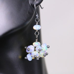 May include: Silver dangle earrings with a cluster of iridescent opal beads and silver beads.