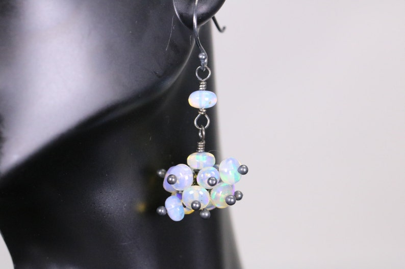 May include: Silver dangle earrings with a cluster of iridescent opal beads and silver beads.