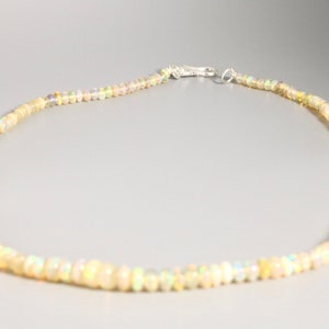 May include: A delicate necklace made of small, iridescent white opal beads. The necklace is strung on a silver chain and has a silver clasp.