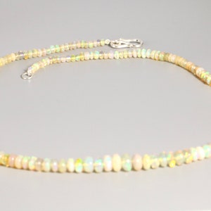 May include: A delicate necklace made of small, iridescent opal beads. The necklace is strung on a silver chain and has a simple clasp.