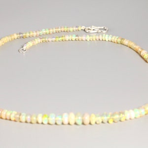 May include: A delicate necklace made of small, iridescent opal beads. The necklace is strung on a silver chain and has a silver clasp.
