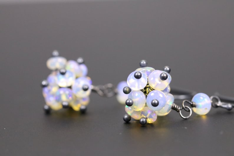 May include: A pair of silver earrings with clusters of iridescent white opal beads and small black beads.