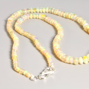 May include: A white opal beaded necklace with a silver clasp. The necklace is made of small, round beads that are strung together on a silver chain.