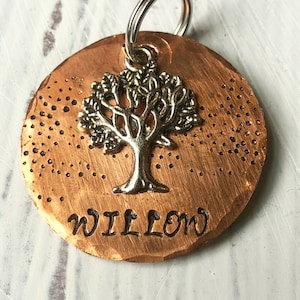 May include: Copper dog tag with a tree design and the name "WILLOW" engraved on it.