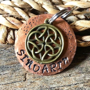 May include: Copper dog tag with a Celtic knot design and the name "Sindarin" engraved on it.