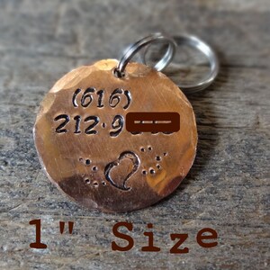 May include: A 1 inch copper dog tag with a hammered finish. The tag has a heart design and the text (616) 212-9---.